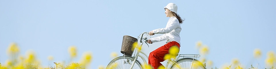Лето. Молодая женщина едет на велосипеде по полю.